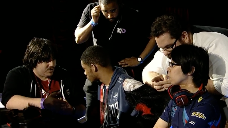 El momento del cambio de asientos. Goichi notablemente molesto mientras su traductor le explica qué está sucediendo, y SonicFox hablando con los jueces pidiendo el cambio.